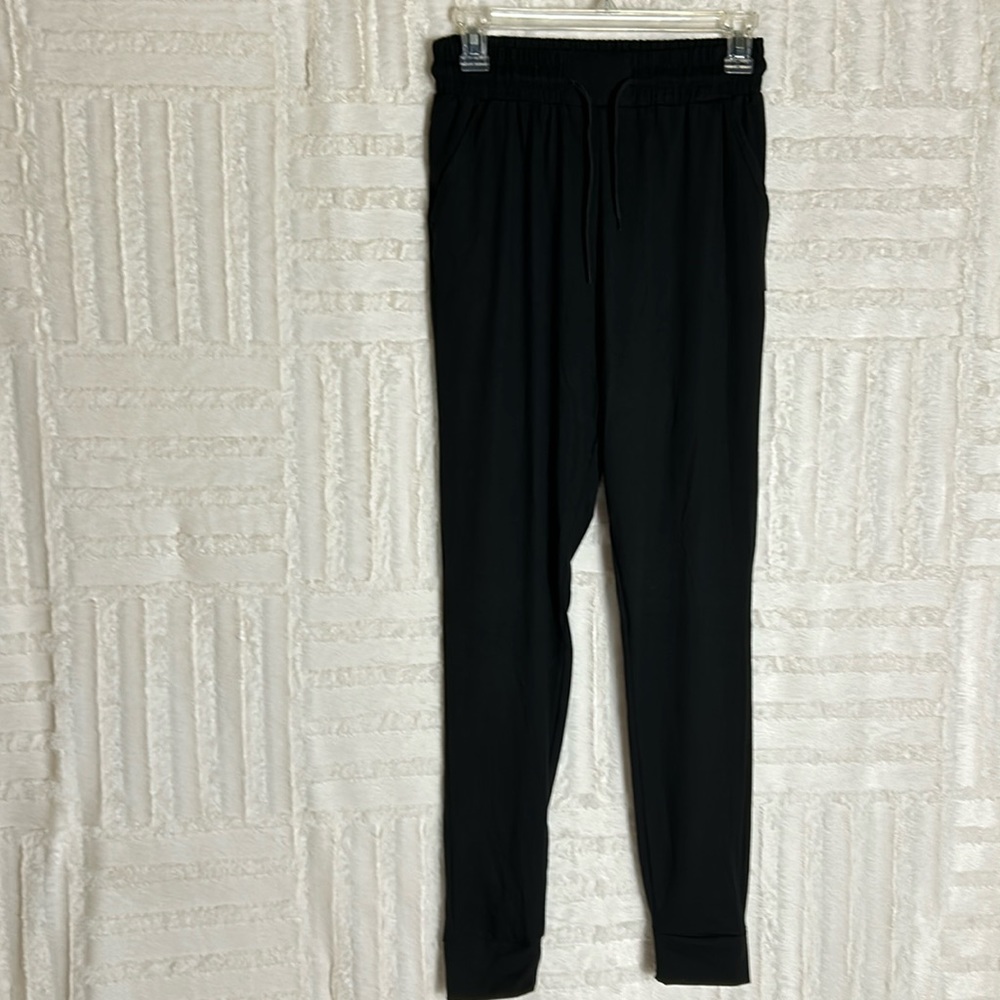Small loose leggings in black. Drawstring waist and cuffed ankles with pockets.